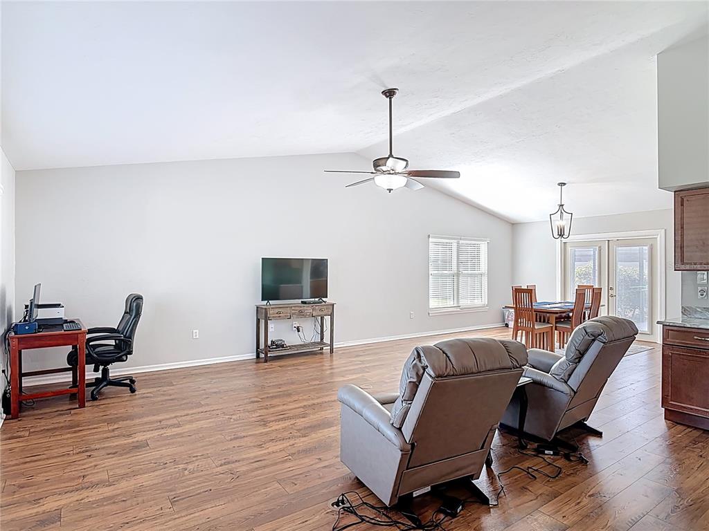 A living room with wood-look flooring, a vaulted ceiling, a ceiling fan, and a desk — 1807 VIRGINIA COURT, TAVARES, FL