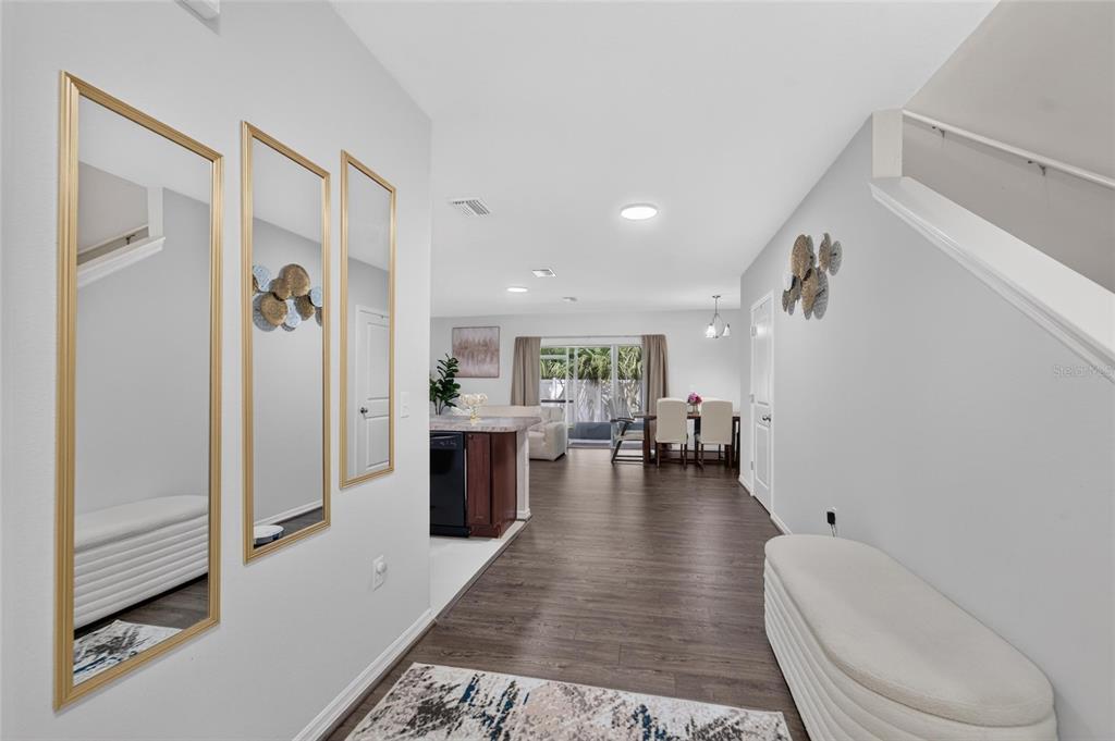 A bright entryway with wood-look flooring leads into an open-concept kitchen and dining area — 12925 SHADY FERN LANE, GIBSONTON, FL
