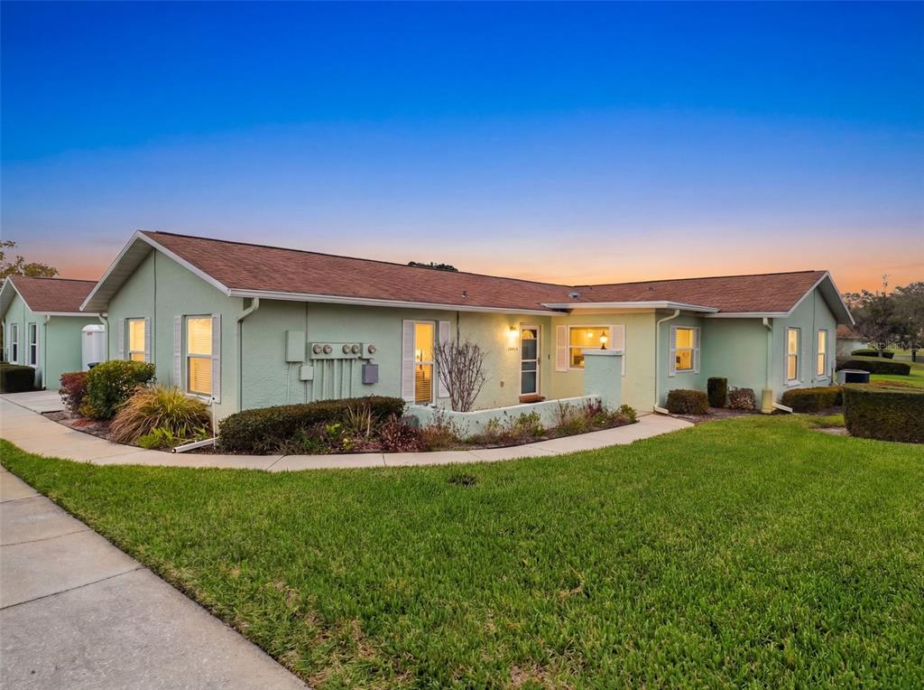 A light green single-story house with a brown shingled roof and a concrete walkway — 11341 DOLLAR LAKE DRIVE UNIT 1, PORT RICHEY, FL