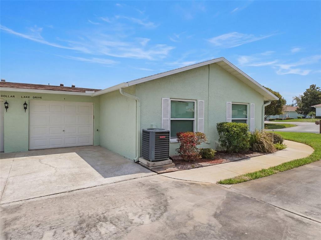 A light green single-story house with a white garage door and an outdoor AC unit — 11341 DOLLAR LAKE DRIVE UNIT 1, PORT RICHEY, FL