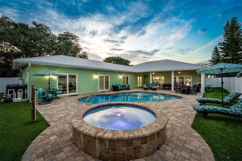 A backyard features a swimming pool, a circular hot tub, and a patio with furniture — 303 HARRISON AVENUE, CAPE CANAVERAL, FL