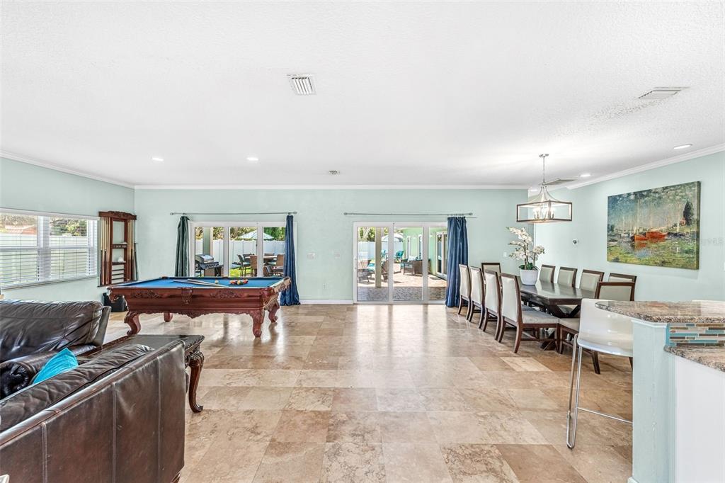 An open-concept living and dining area features tile flooring, a pool table, and sliding glass doors — 303 HARRISON AVENUE, CAPE CANAVERAL, FL