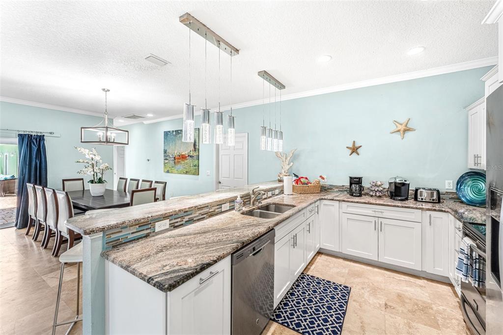 A kitchen with granite countertops, white cabinets, and a breakfast bar overlooks a dining area — 303 HARRISON AVENUE, CAPE CANAVERAL, FL