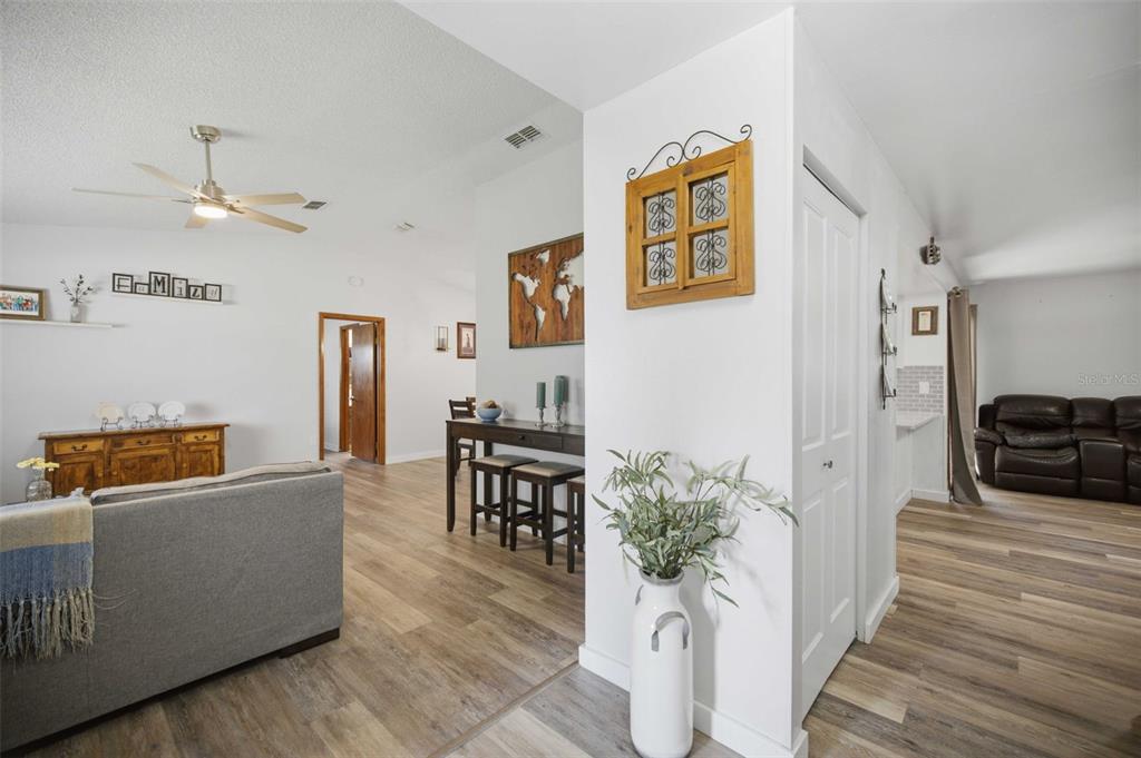 A living room with wood-look flooring, a ceiling fan, and a dining area in the background — 11089 SW 78TH COURT, OCALA, FL