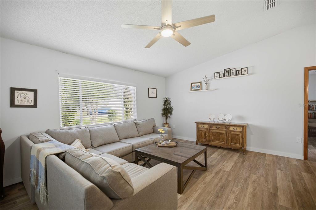 A living room features a gray sectional sofa, a wooden coffee table, and wood-look flooring — 11089 SW 78TH COURT, OCALA, FL