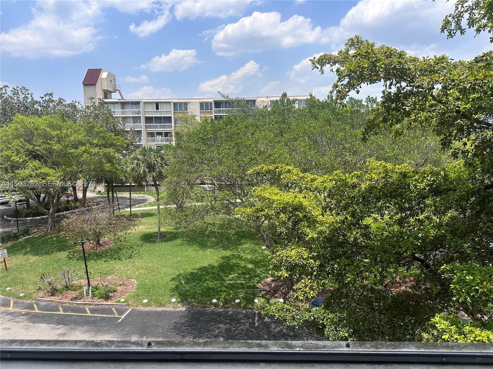 An elevated view shows a grassy courtyard with trees and a multi-story apartment building — 7021 Environ Boulevard # 317, Lauderhill FL 33319, LAUDERHILL, FL