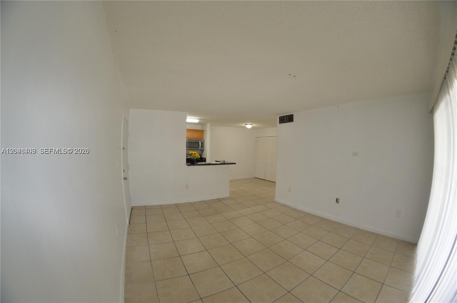 An open-concept living area features light-colored tile flooring and a pass-through kitchen counter — 15630 SW 80th St # 210, Miami FL 33193, MIAMI, FL