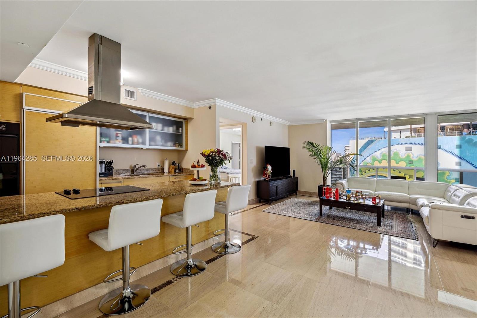 An open-concept living area features a kitchen with a granite island and white bar stools — 1800 S Ocean Dr # 1010, Hallandale Beach FL 33009, HALLANDALE BEACH, FL