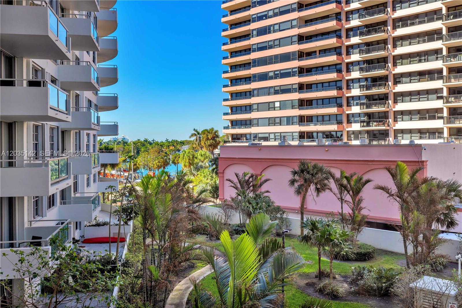 An exterior view shows two high-rise apartment buildings flanking a courtyard with palm trees — 5161 Collins Ave # 310, Miami Beach FL 33140, MIAMI BEACH, FL