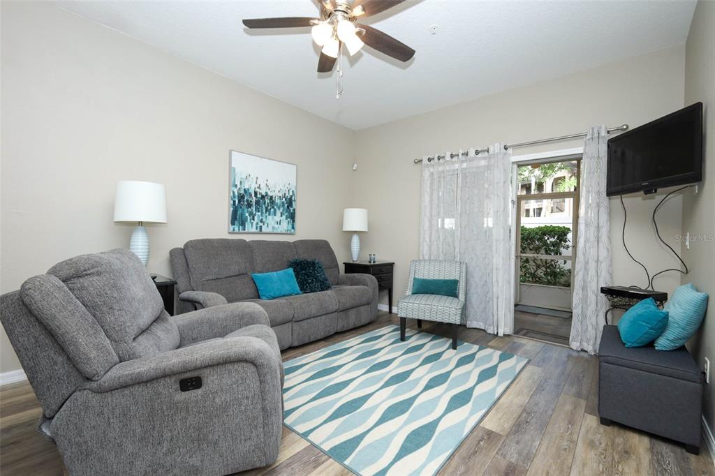 A living room features gray furniture, a patterned area rug, and a sliding glass door — 694 SEABROOK COURT UNIT 101, ALTAMONTE SPRINGS, FL