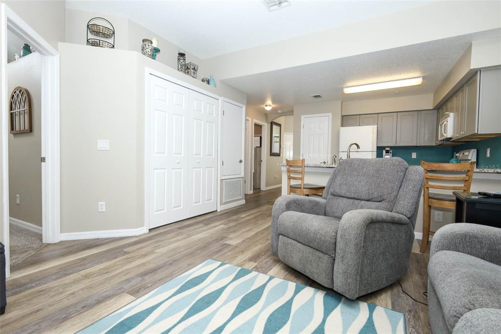 A living room with wood-look flooring, a gray recliner, and an open kitchen with gray cabinets — 694 SEABROOK COURT UNIT 101, ALTAMONTE SPRINGS, FL