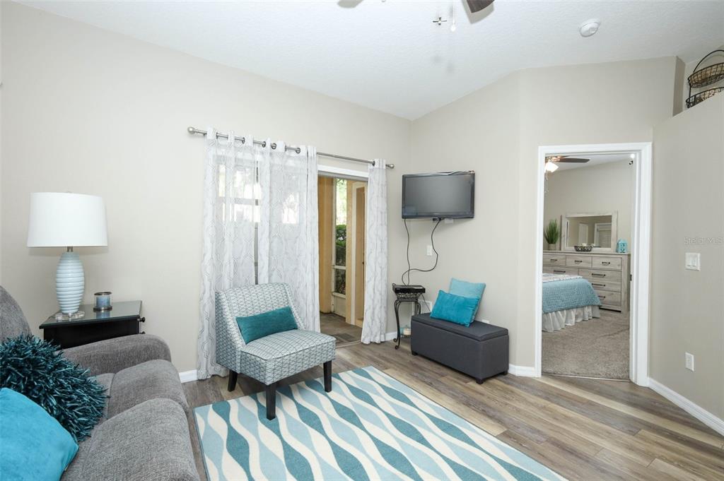 A living room features light walls, wood-look flooring, a patterned rug, and a doorway — 694 SEABROOK COURT UNIT 101, ALTAMONTE SPRINGS, FL