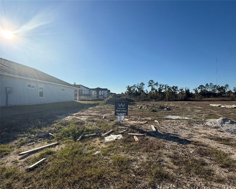 A vacant residential lot with a construction sign stands next to a house under construction — 1132 SW 67TH WAY, GAINESVILLE, FL