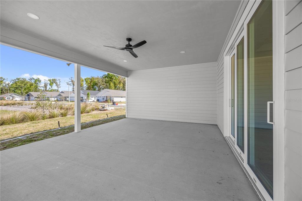 A covered concrete patio features a ceiling fan and sliding glass doors leading indoors — 1132 SW 67TH WAY, GAINESVILLE, FL