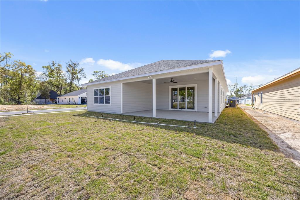 The exterior view shows the back of a light gray house with a covered patio — 1132 SW 67TH WAY, GAINESVILLE, FL