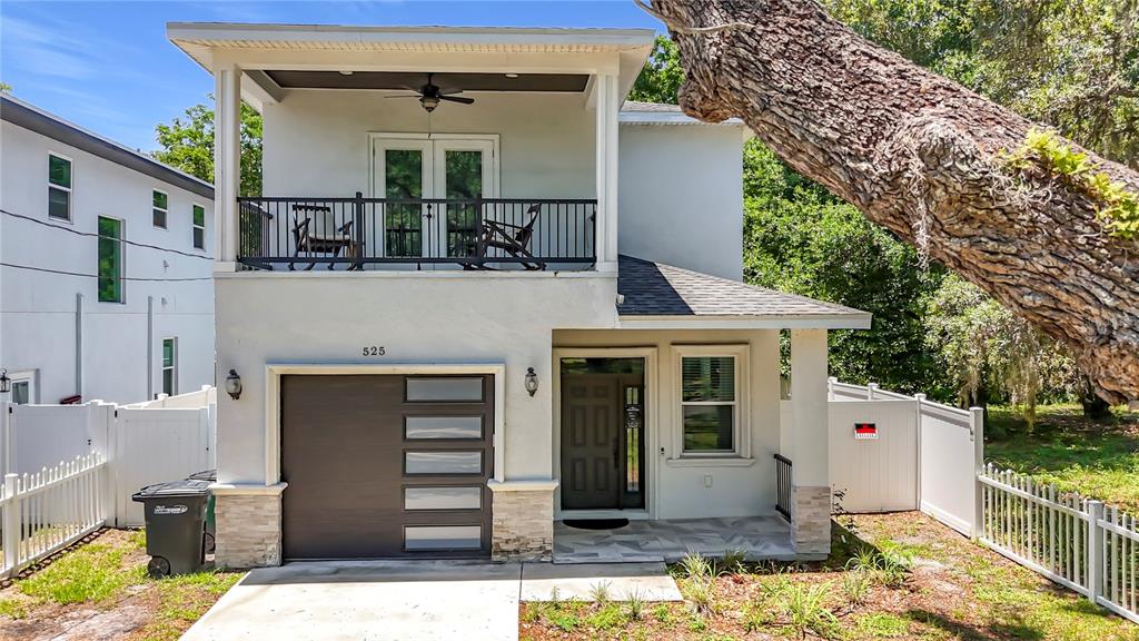 A two-story house with a garage, a second-floor balcony, and a white picket fence — 525 ELM STREET, SAFETY HARBOR, FL