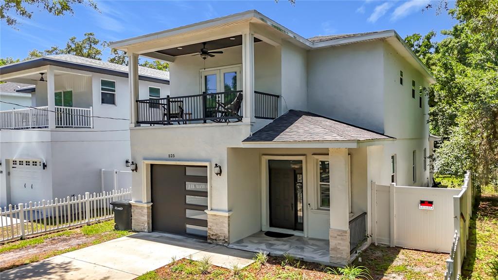 A two-story house with a balcony, a garage, and a white fence — 525 ELM STREET, SAFETY HARBOR, FL