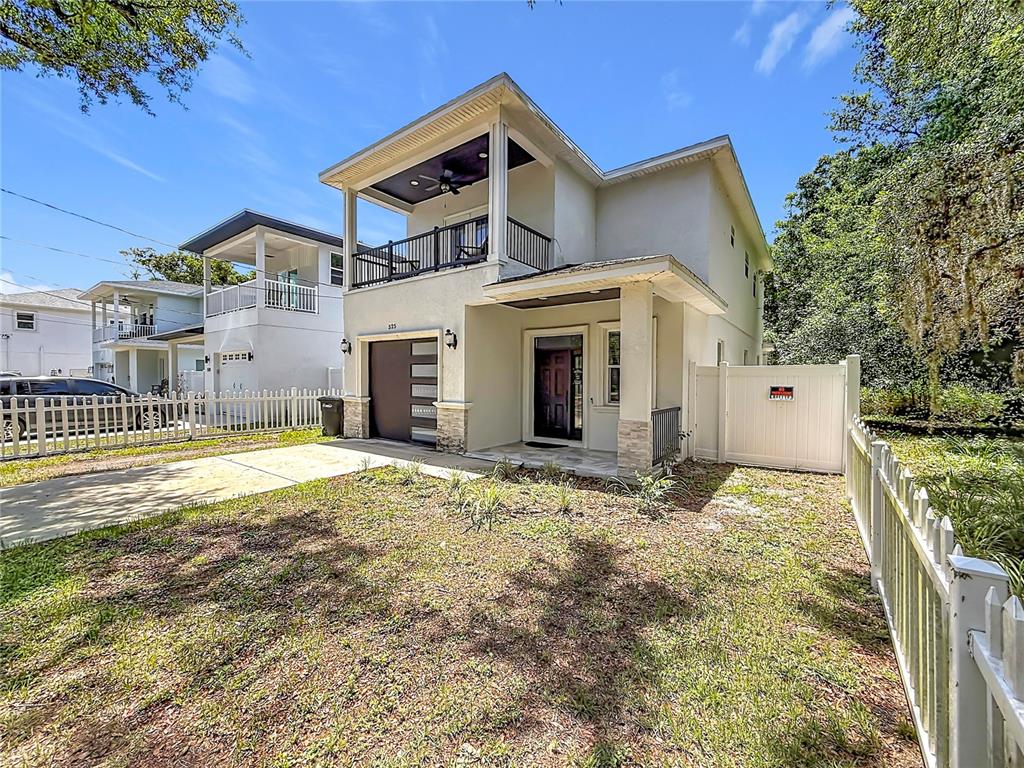 A two-story house with a balcony, garage, and white picket fence under a blue sky — 525 ELM STREET, SAFETY HARBOR, FL