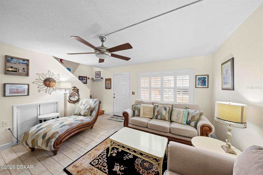 A living room features a beige sofa, a chaise lounge, a ceiling fan, and tile flooring — 3750 S ATLANTIC AVENUE UNIT 190, DAYTONA BEACH, FL