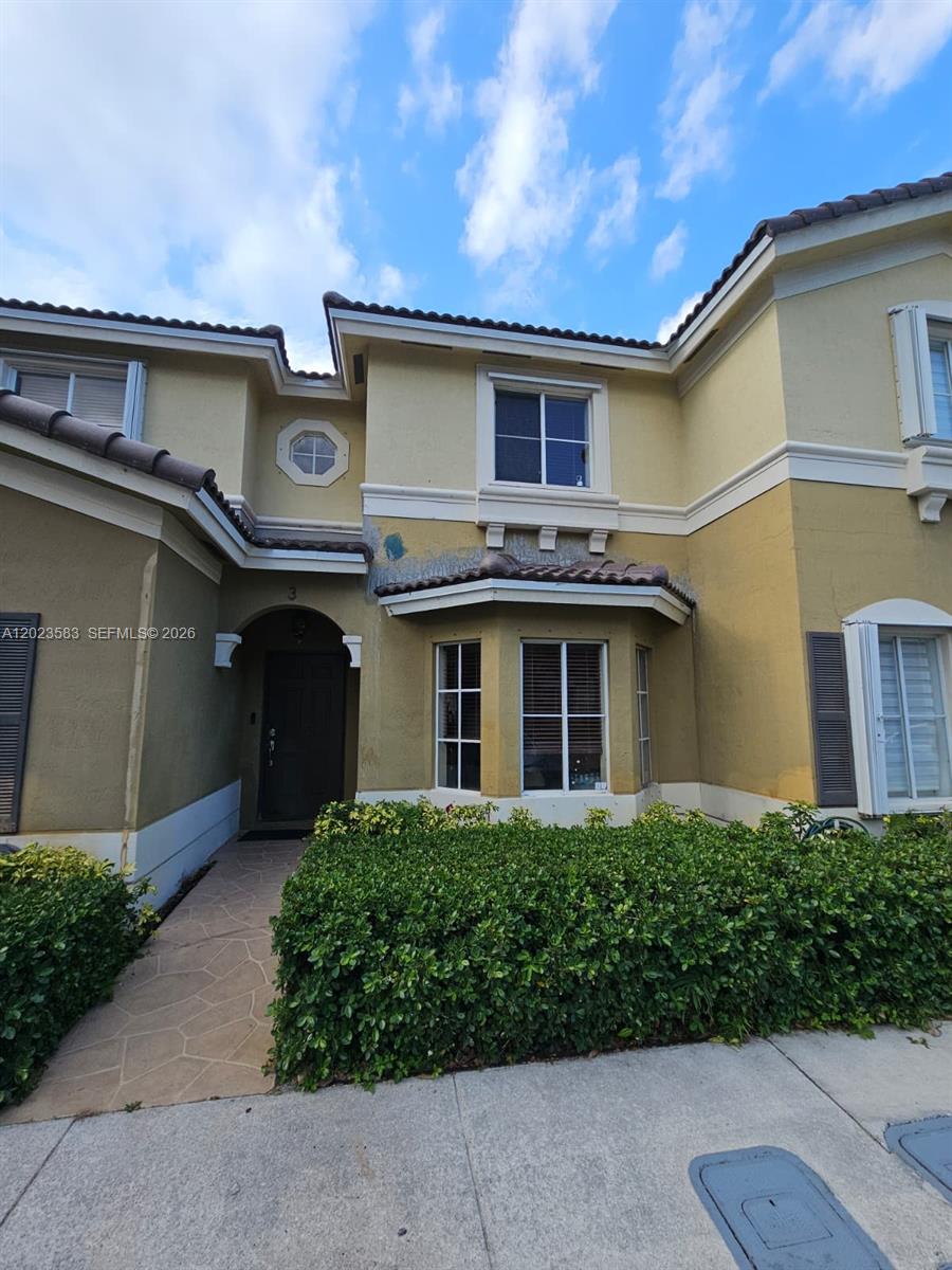 A two-story townhouse exterior features a tan stucco facade, a dark front door, and landscaping — 8960 W Flagler St # 3, Miami FL 33174, MIAMI, FL