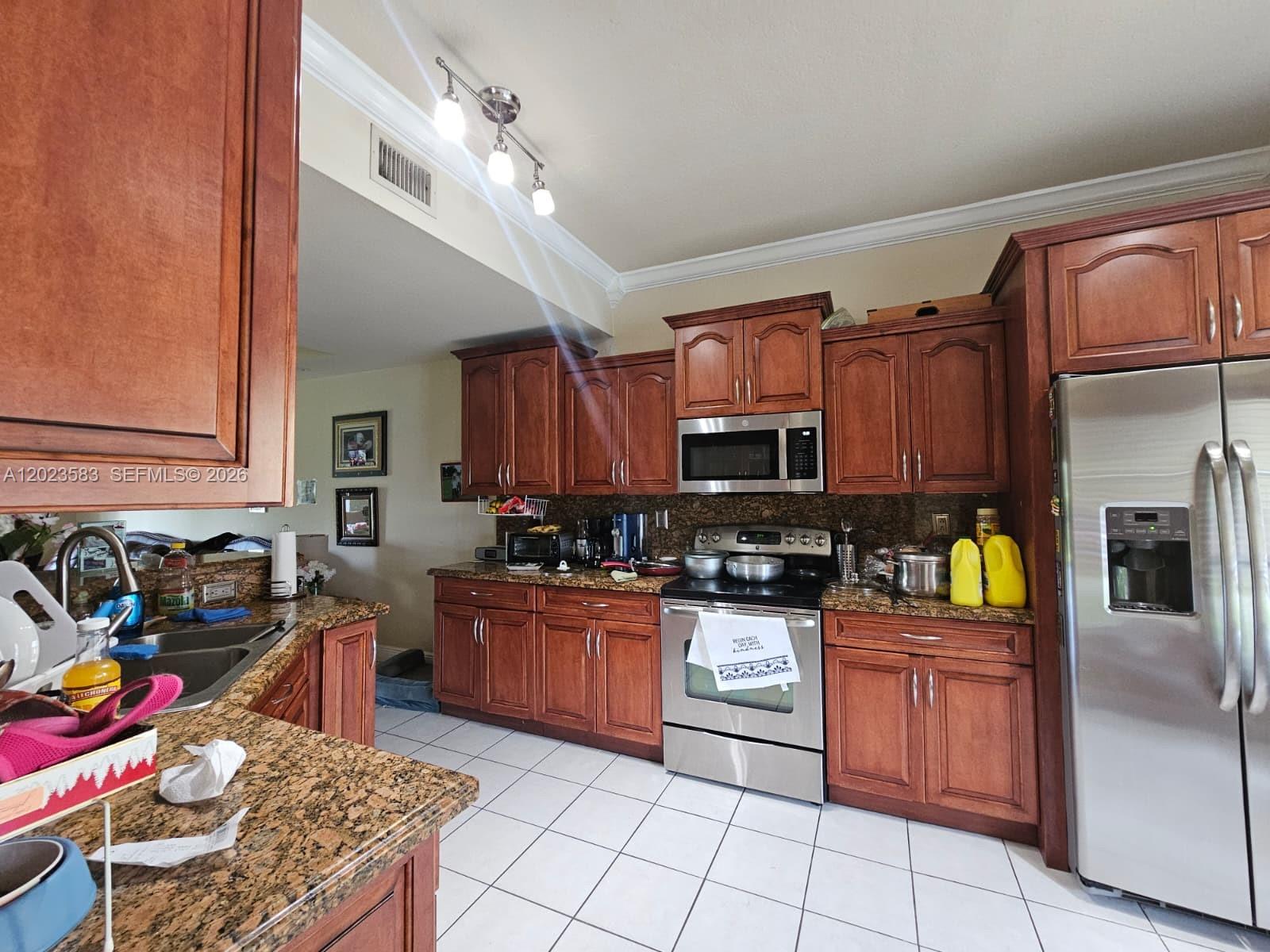 A kitchen features wood cabinets, granite countertops, stainless steel appliances, and white tile flooring — 8960 W Flagler St # 3, Miami FL 33174, MIAMI, FL