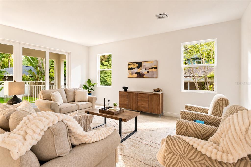 A living room features beige sofas, patterned armchairs, a wooden coffee table, and large windows — 4614 W EUCLID AVENUE, TAMPA, FL