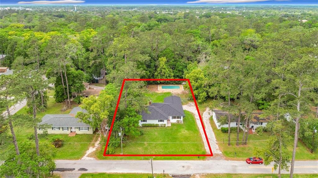 An aerial view shows a single-story house with a pool on a wooded lot — 1220 NE 16TH AVENUE, OCALA, FL