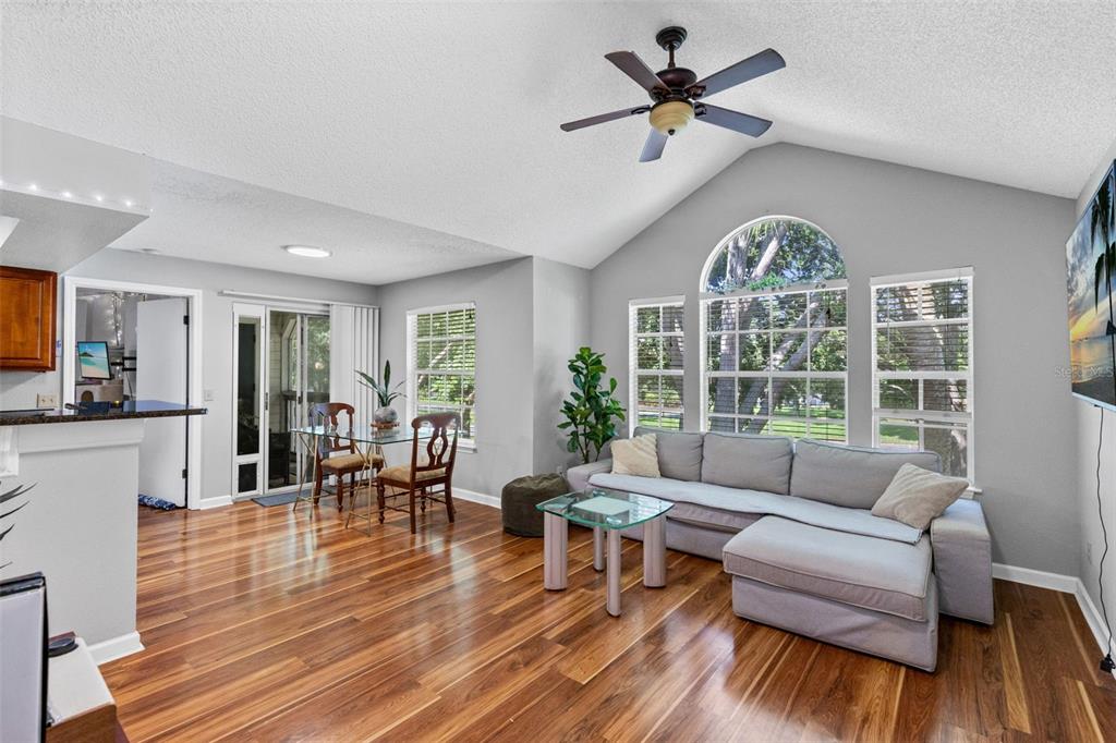 A living room with hardwood floors, a gray sectional sofa, and a vaulted ceiling — 1021 S HIAWASSEE ROAD UNIT 3928, ORLANDO, FL