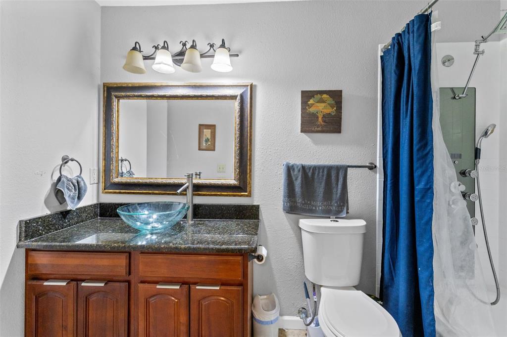 A bathroom features a wooden vanity with a glass vessel sink, a mirror, and a shower — 1021 S HIAWASSEE ROAD UNIT 3928, ORLANDO, FL