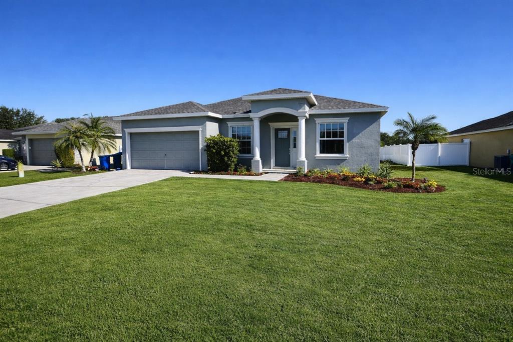 A single-story gray house with a two-car garage and a front lawn under blue sky — 1192 NORMANDY, WINTER HAVEN, FL