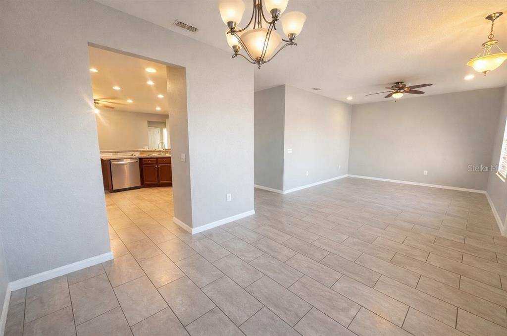 An open-concept living and dining area with light gray walls and large tile flooring — 1192 NORMANDY, WINTER HAVEN, FL