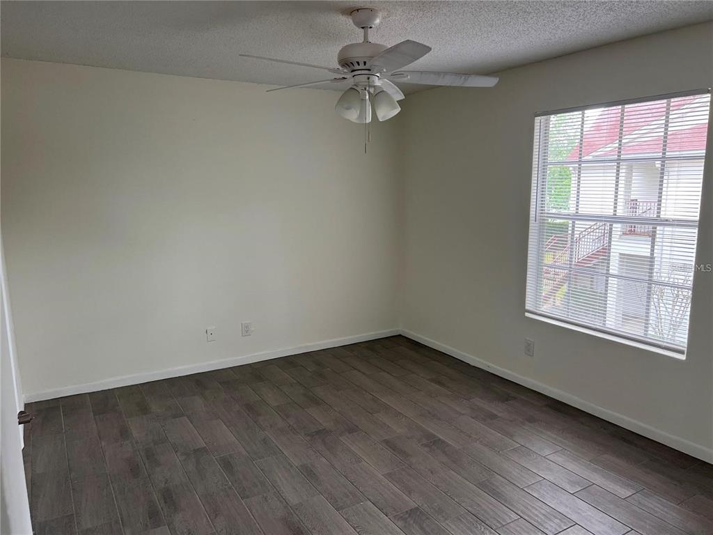 An empty bedroom features white walls, dark wood-look flooring, a ceiling fan, and a window — 11568 WESTWOOD BOULEVARD UNIT 1021, ORLANDO, FL