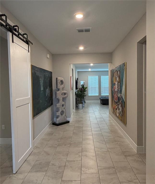 A tiled hallway features a white sliding barn door, two large paintings, and a sculpture — 4434 NW 54TH TERRACE, OCALA, FL