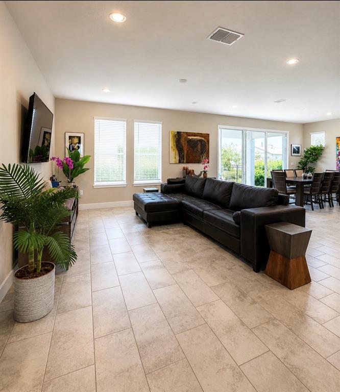 A living room features a dark leather sectional, tile flooring, and a dining area nearby — 4434 NW 54TH TERRACE, OCALA, FL