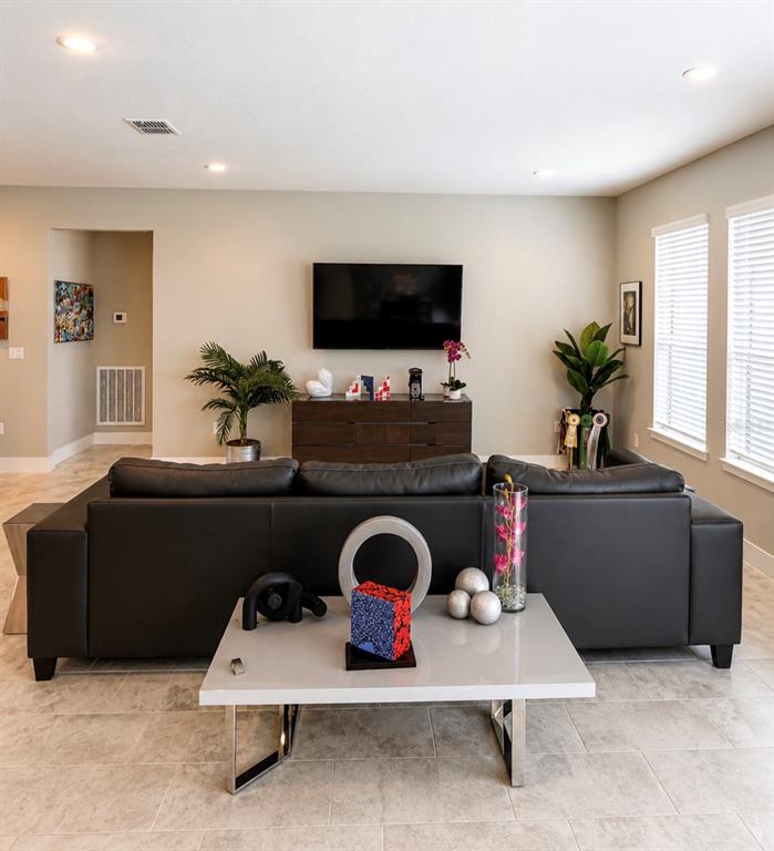 A living room features a dark leather sectional sofa, a coffee table, and a television — 4434 NW 54TH TERRACE, OCALA, FL