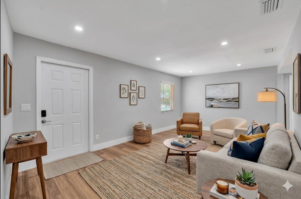 A living room features light gray walls, wood-look flooring, a sofa, armchairs, and a rug — 125 E Hart Street, Lantana FL 33462, LANTANA, FL