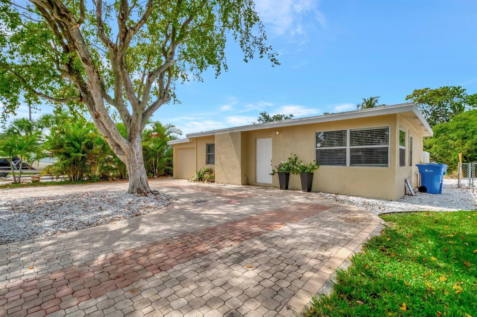 A single-story house with a paved driveway, a large tree, and a blue trash bin — 125 E Hart Street, Lantana FL 33462, LANTANA, FL