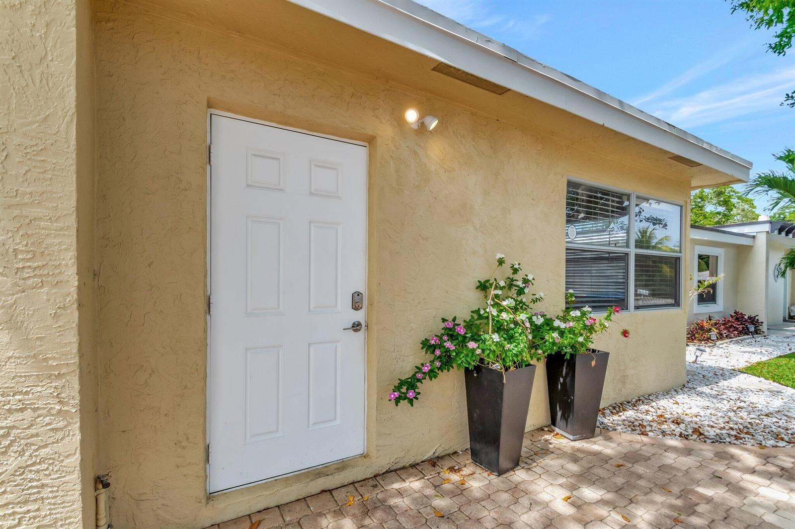 A white door with a smart lock sits on a beige stucco exterior wall — 125 E Hart Street, Lantana FL 33462, LANTANA, FL
