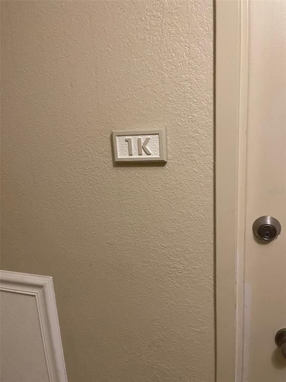 A beige wall features a small rectangular sign labeled 1K next to a door — 2755 COCONUT BAY LN LANE UNIT 119 (1K), SARASOTA, FL