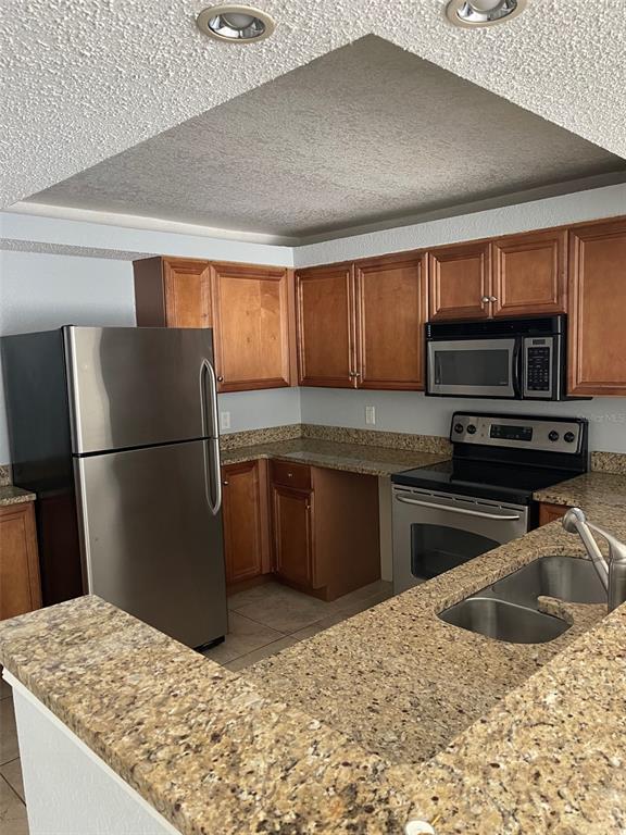 A kitchen features wood cabinets, granite countertops, stainless steel appliances, and a recessed ceiling — 2755 COCONUT BAY LN LANE UNIT 119 (1K), SARASOTA, FL