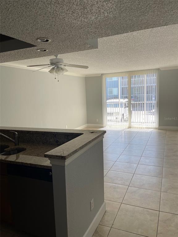 A kitchen island with granite countertops overlooks a living area with tile floors and sliding doors — 2755 COCONUT BAY LN LANE UNIT 119 (1K), SARASOTA, FL