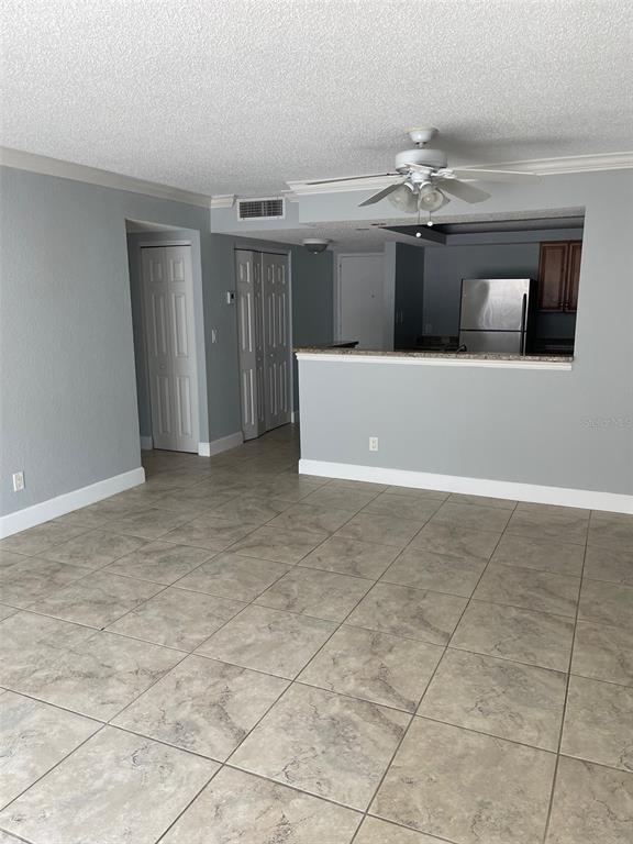 A living room with tile flooring, a ceiling fan, and an open kitchen pass-through — 2755 COCONUT BAY LN LANE UNIT 119 (1K), SARASOTA, FL
