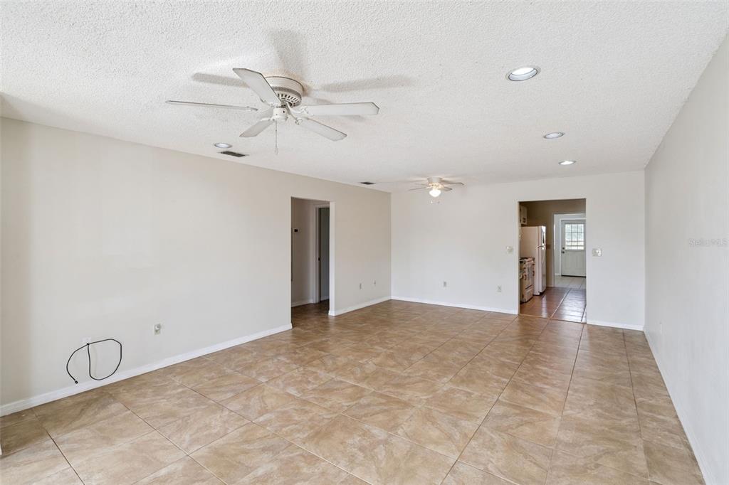 A spacious living room features beige tile flooring, two ceiling fans, and recessed lighting — 30213 TAVARES RIDGE BOULEVARD UNIT 30213, TAVARES, FL