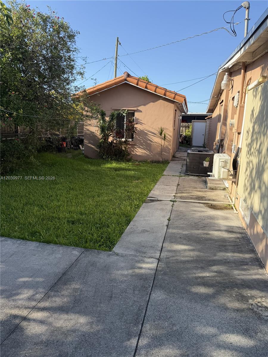 A backyard view shows a small detached building, a concrete walkway, and a grassy lawn — MIAMI, FL