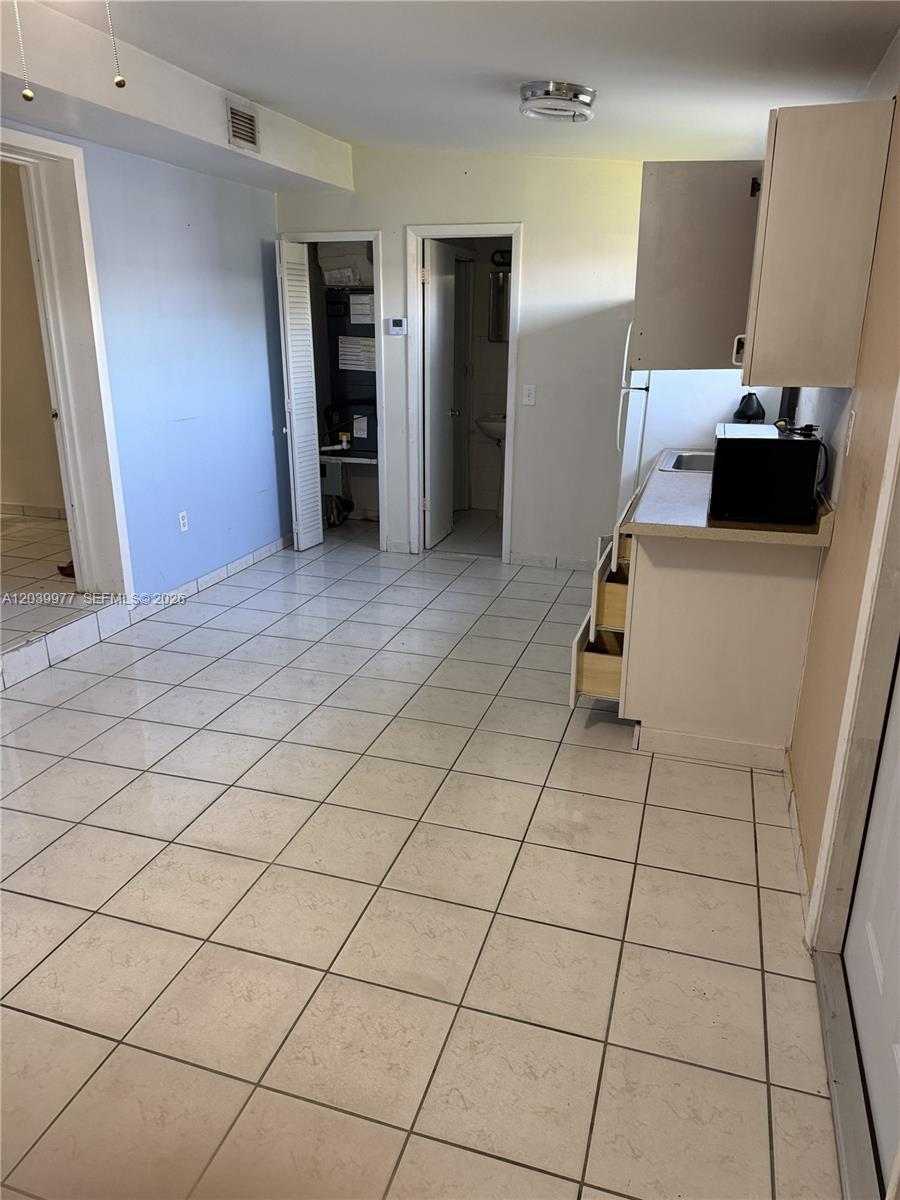 A small kitchen area features white cabinets, a microwave, and light-colored floor tiles — MIAMI, FL