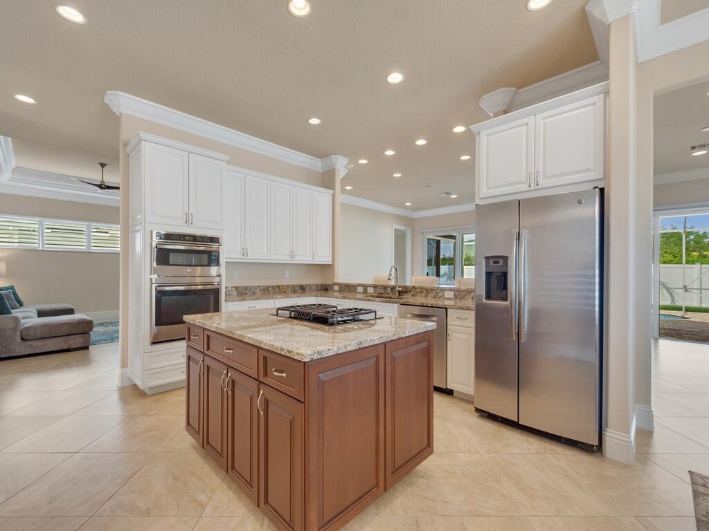 A kitchen features a brown wooden island, white cabinets, stainless steel appliances, and tile flooring — 445 Wingate Terrace SW, Vero Beach FL 32968, VERO BEACH, FL