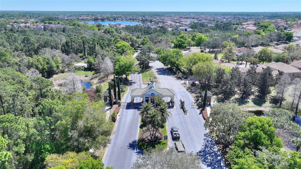 An aerial view shows a gated community entrance with a guardhouse, palm trees, and roads — 419 CHELSEA AVENUE, DAVENPORT, FL