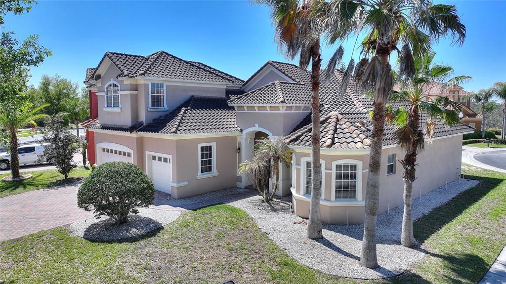 An exterior view of a two-story beige house with a tiled roof and palm trees — 419 CHELSEA AVENUE, DAVENPORT, FL