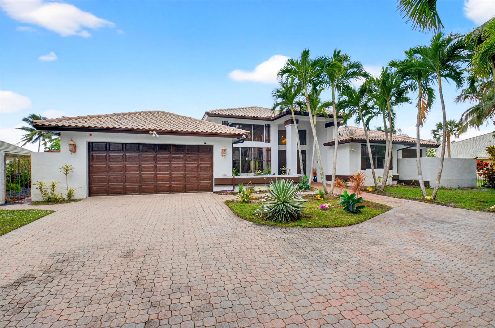 A white house with a brown garage door and a paved driveway under a blue sky — 1940 SW 7th Place, Boca Raton FL 33486, BOCA RATON, FL