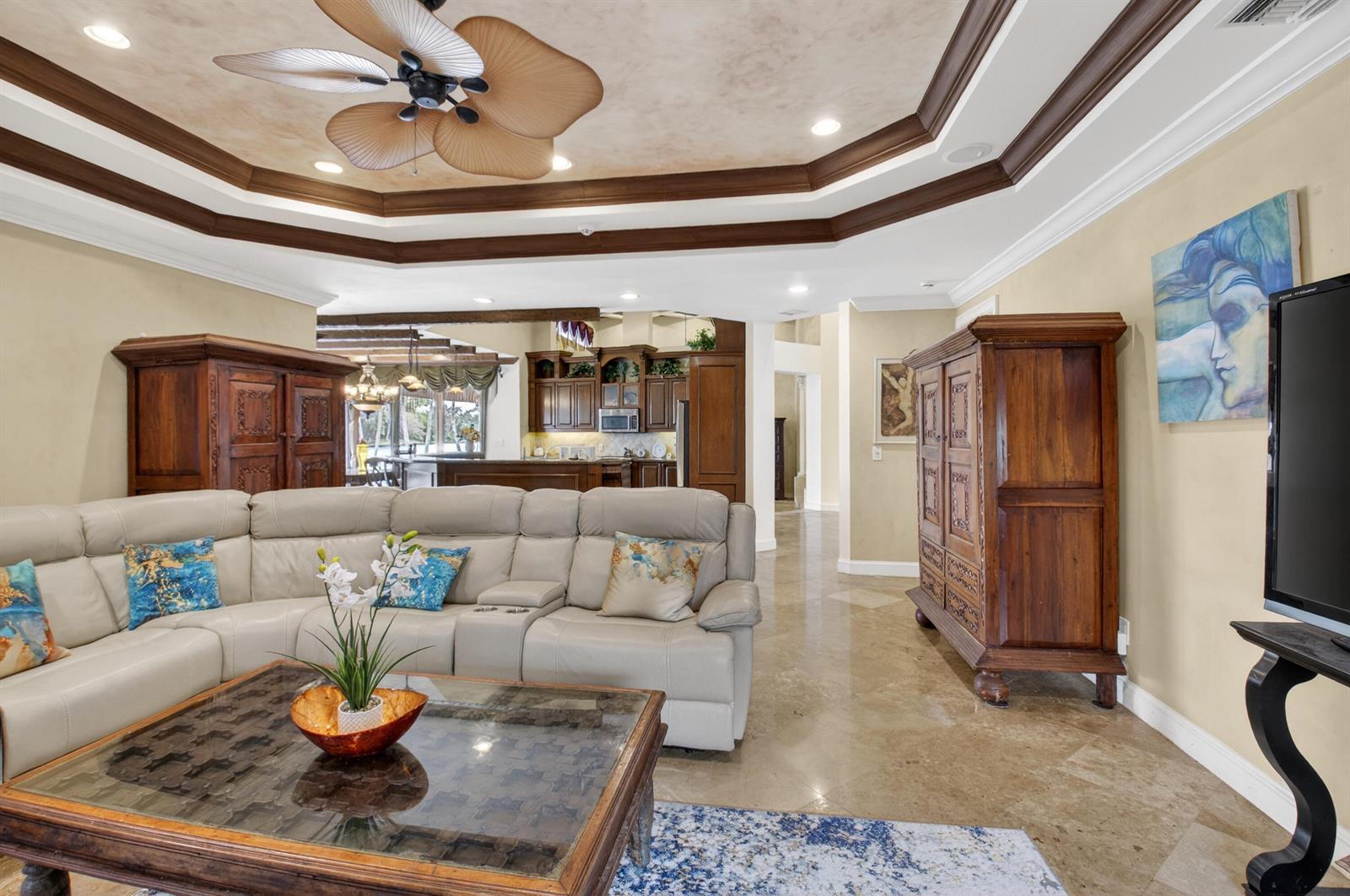 A living room features a tray ceiling, leather sectional, wooden armoires, and tile flooring — 1940 SW 7th Place, Boca Raton FL 33486, BOCA RATON, FL